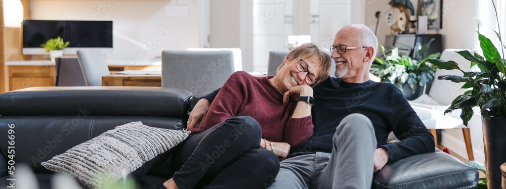 Older couple laughing together on a couch at home